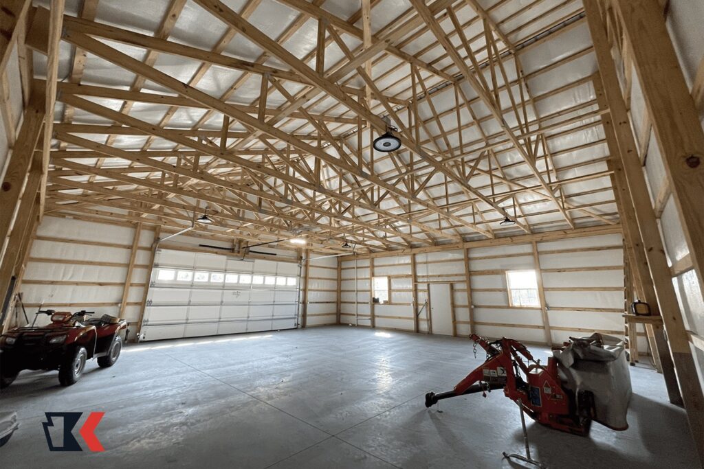interior view of metal farm workshop building with large garage door, side entrance door, and two windows
